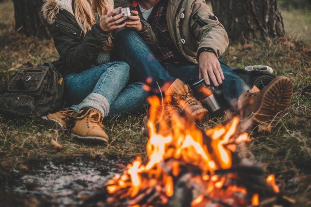 two people sitting around a campfire